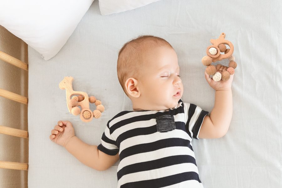 Portrait of sleeping newborn baby holding his toy in hand, top view